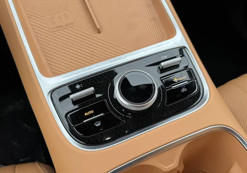 Gros plan sur la console centrale beige du Geely STARRAY 1.5 EM-i avec commandes climatiques et surface de recharge sans fil.