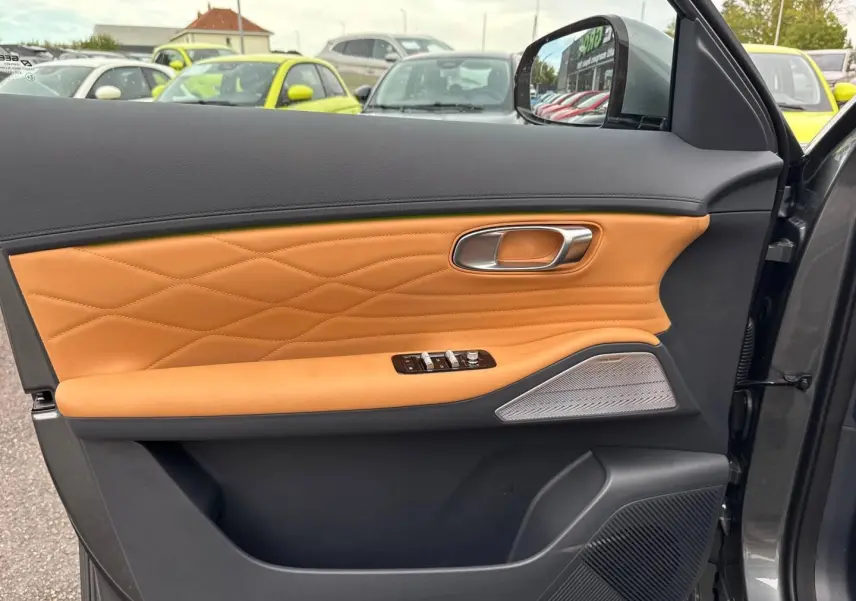 Vue intérieure côté gauche de la porte avant d’un Geely STARRAY 2026 Volcanic Grey avec garniture cuir marron et haut-parleur Harman Kardon.