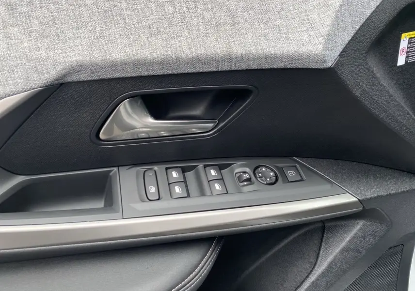 Gros plan sur la commande de porte côté gauche du Peugeot 3008 blanc Okenite, mettant en valeur les boutons de réglage des vitres et des rétroviseurs.