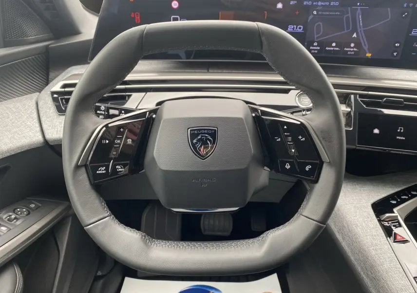 Volant cuir noir au design carré du Peugeot 3008 hybride 2024 avec tableau de bord numérique et écran tactile visible.