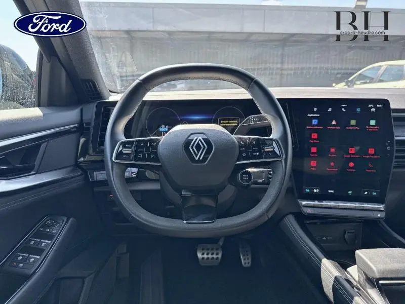 Vue intérieure centrée sur le volant Renault du tableau de bord du Renault Austral 2024 noir étoilé avec écran tactile.