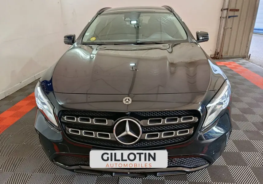 Vue frontale d'un Mercedes GLA 220 d noir avec calandre distinctive et phares LED, stationné en intérieur.