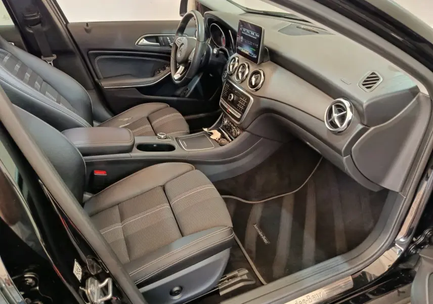 Vue intérieure côté conducteur du Mercedes GLA 220 d noir, avec tableau de bord moderne et sièges en tissu noir.