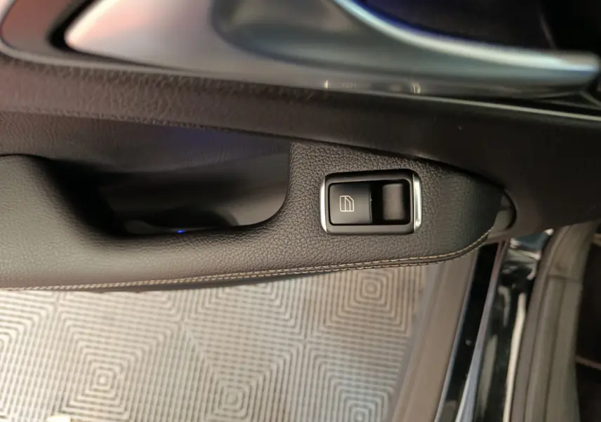 Bouton de commande de lève-vitre sur la porte côté gauche d'une Mercedes GLA 220 d noire, intérieur cuir noir.