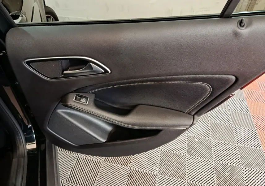 Porte intérieure côté gauche en cuir noir avec poignée argentée et bouton de commande de vitre, Mercedes GLA 220 d 2018.
