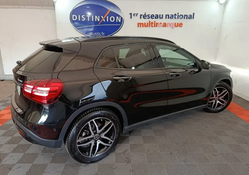 Mercedes GLA 220 d noir vue 3/4 arrière droit, avec jantes alliage et vitres teintées en intérieur showroom.