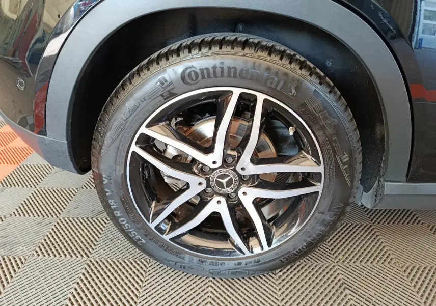 Gros plan sur la roue avant gauche noire d'un Mercedes GLA 220 d avec jante alliage noir et argentée Continental.