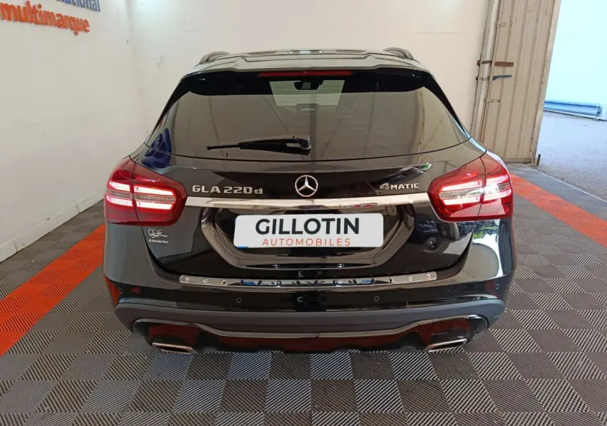 Vue arrière d'un Mercedes GLA 220 d noir avec feux LED allumés et logo 4Matic visible sur parking intérieur.