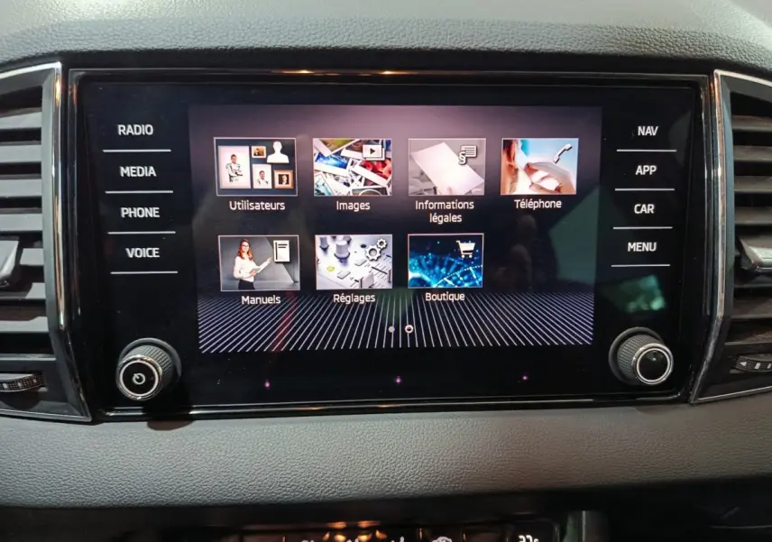 Écran tactile central allumé du tableau de bord gris du Skoda Karoq 2024, affichant menu multimédia et réglages.