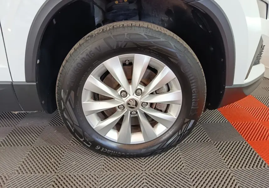 Gros plan sur la roue avant droite argentée d’un SKODA KAROQ blanc avec jante en alliage et pneu Continental.