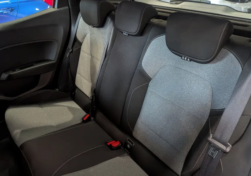 Vue intérieure des sièges arrière en tissu gris et noir de la Renault Clio V 2024, avec ceintures de sécurité visibles.
