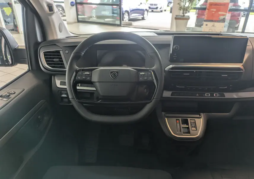 Vue intérieure frontale du tableau de bord noir du Peugeot Traveller 2026 avec volant cuir et écran tactile.