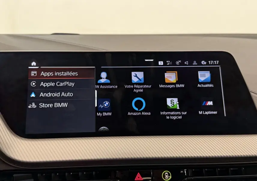 Écran tactile central affichant les applications connectées dans l’habitacle beige d’une BMW Série 1 noire.