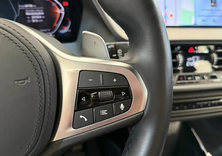 Gros plan sur les commandes multifonctions du volant cuir noir d’une BMW Série 1 120i Edition M Sport Pro 2023.