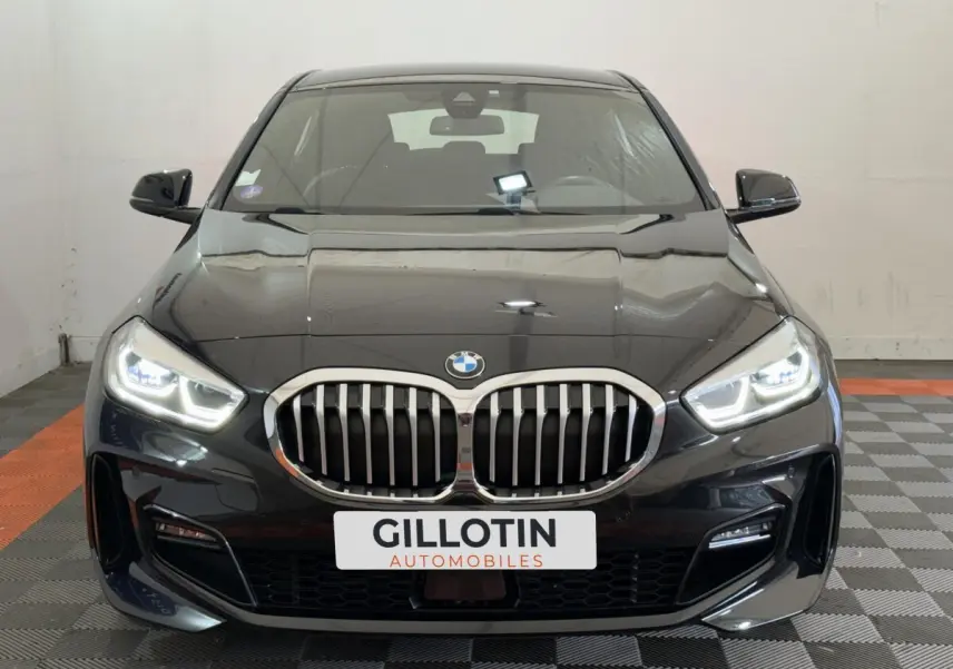 BMW Série 1 120i Edition M Sport Pro noire vue de face avec phares LED allumés et calandre chromée distinctive.