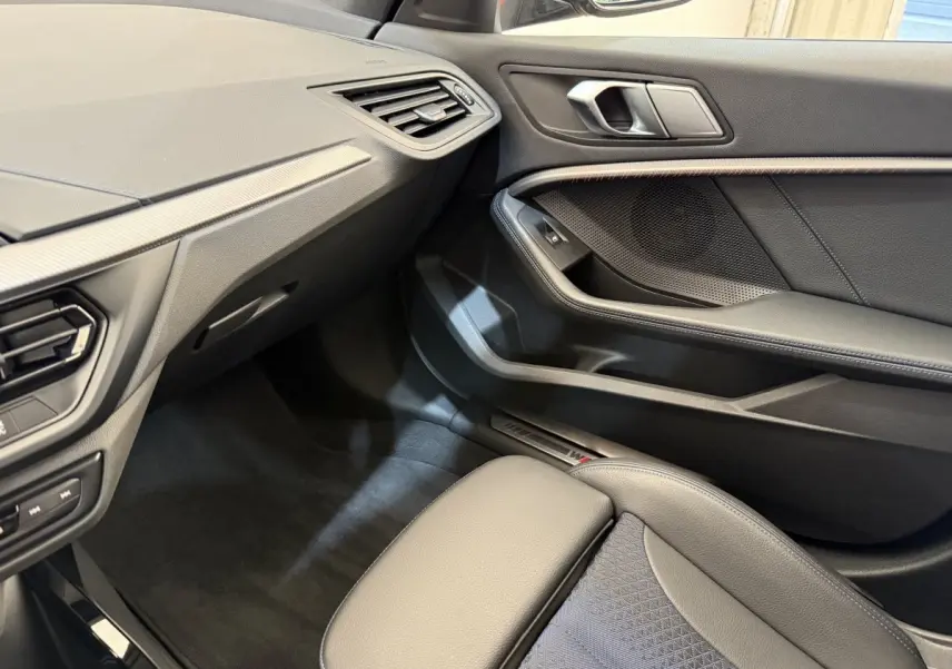Vue intérieure côté passager de la BMW Série 1 120i Edition M Sport Pro 2023, avec sellerie noire et détails M Sport.