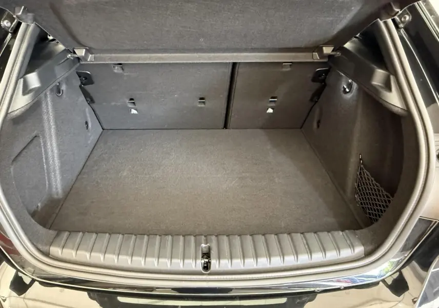 Coffre ouvert de BMW Série 1 120i noir, vue arrière, montrant un espace de chargement propre et spacieux.