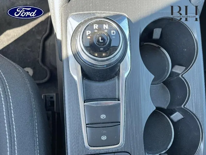 Gros plan sur la console centrale du Ford Kuga 2022 avec molette de boîte auto et porte-gobelets noirs.