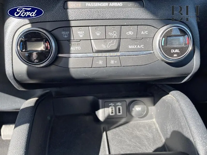 Vue rapprochée de la console centrale du Ford Kuga 2022 avec commandes climatisation bi-zone et prises USB visibles.