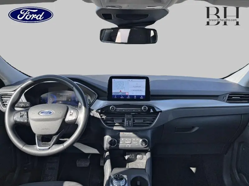 Vue intérieure frontale du tableau de bord du Ford Kuga 2022 avec écran tactile et volant cuir multifonction noir.