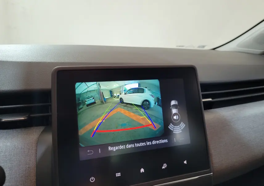 Écran tactile central montrant la caméra de recul avec vue arrière d'une Renault Clio gris foncé stationnée en intérieur.