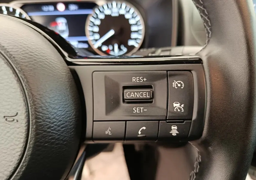 Gros plan sur les commandes du régulateur de vitesse au volant cuir noir du Nissan Qashqai e-Power 2024.