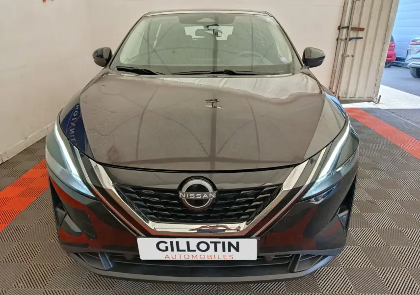 Vue avant d'un Nissan Qashqai e-Power noir avec calandre chromée et phares LED allumés en intérieur showroom.