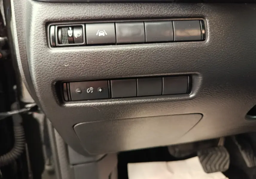 Vue rapprochée des commandes de réglage d’éclairage et d’aide à la conduite sur le tableau de bord noir du Nissan Qashqai e-Power 2024.