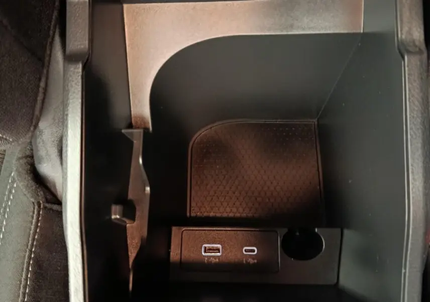 Vue plongeante sur le rangement central noir du Nissan Qashqai e-Power 2024 avec ports USB et prise 12V intégrés.