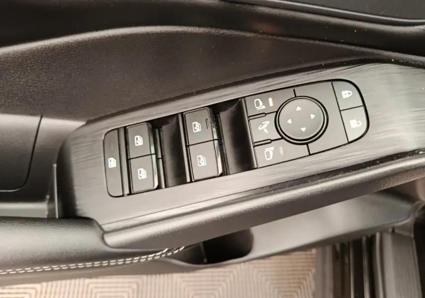 Gros plan sur les commandes de lève-vitres et rétroviseurs côté conducteur du Nissan Qashqai e-Power noir 2024.
