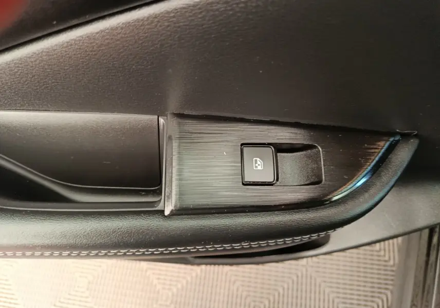 Détail de la commande de lève-vitre électrique sur la porte intérieure côté conducteur du Nissan Qashqai noir 2024.