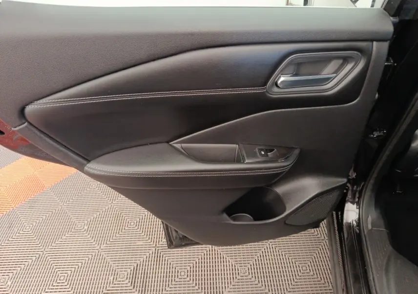 Vue rapprochée de la porte intérieure côté conducteur noire du Nissan Qashqai e-Power 2024 avec poignée et commande de lève-vitre.