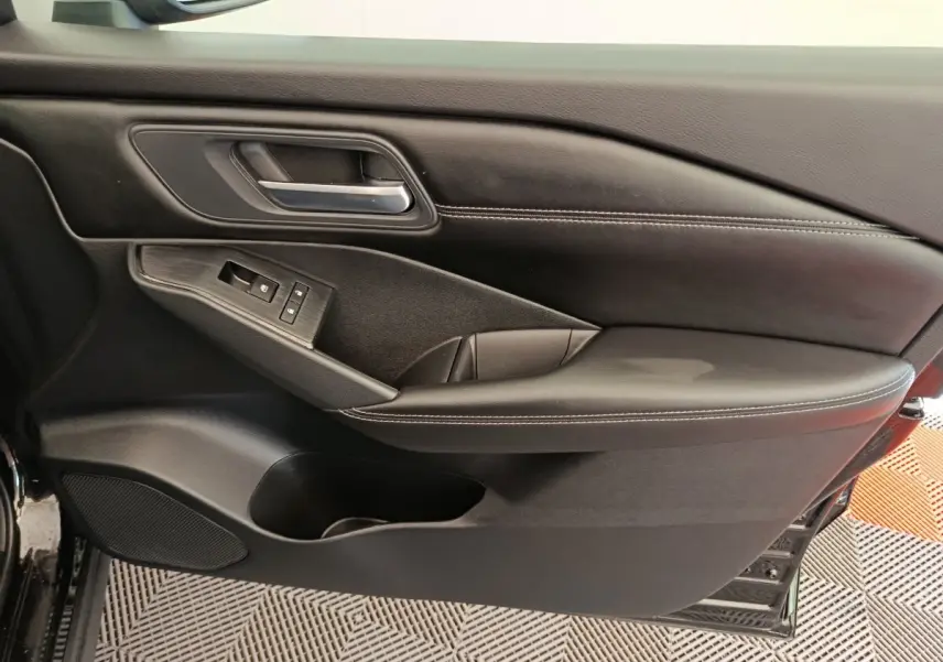 Gros plan sur la porte avant gauche noire du Nissan Qashqai e-Power 2024 avec commandes de lève-vitres et poignée intégrée.
