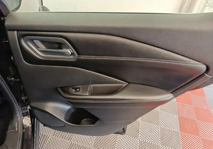 Gros plan sur la porte arrière gauche noire du Nissan Qashqai e-Power 190 Business Edition 2024 avec surpiqûres blanches.