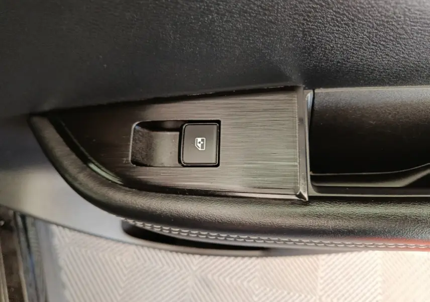 Gros plan sur le bouton de lève-vitre électrique noir sur la porte intérieure côté conducteur du Nissan Qashqai e-Power 2024.