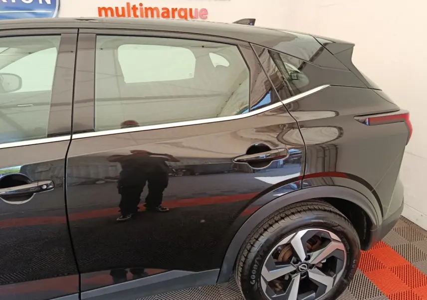 Vue latérale droite du Nissan Qashqai e-Power 190 Business Edition BVA noir, mettant en valeur la roue arrière et la ligne de caisse chromée.
