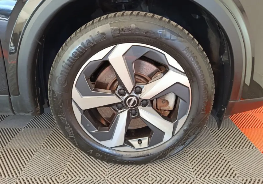 Gros plan sur la roue avant droite du Nissan Qashqai noir 2024 avec jante alliage bicolore et pneu Continental.