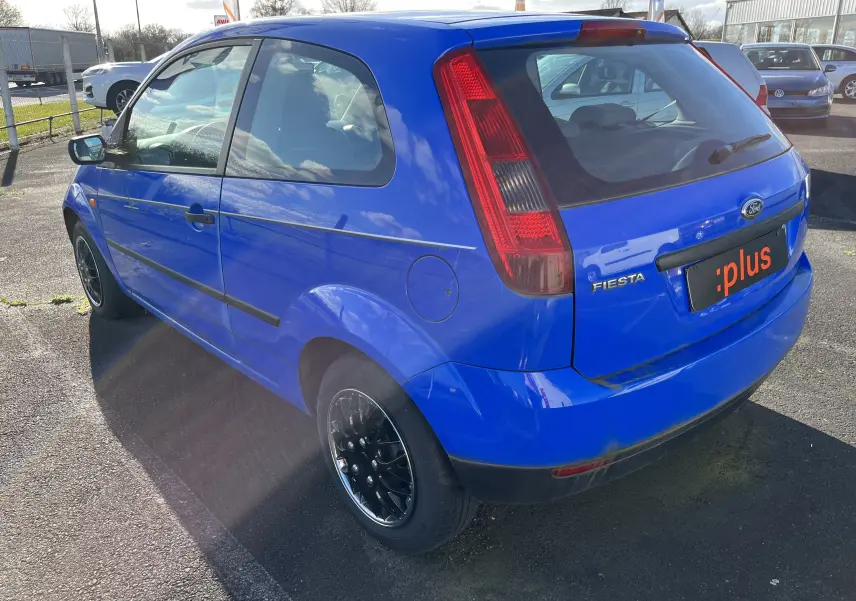 Vue 3/4 arrière droite d'une Ford Fiesta 3 portes bleue de 2003 avec jantes noires et feux arrière verticaux.