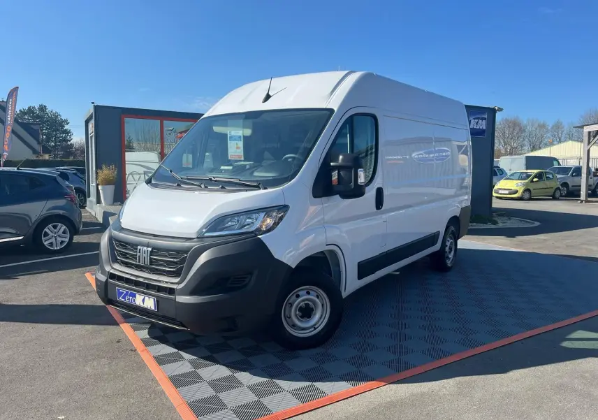 FIAT Ducato Fourgon blanc vu en 3/4 avant droit sur parking, avec calandre noire et jantes acier simples.