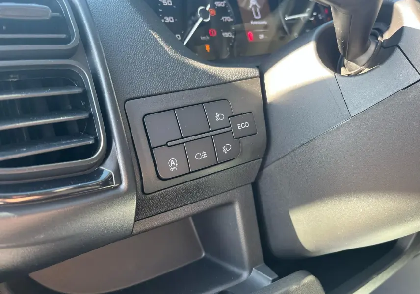 Gros plan sur les commandes d'éclairage et mode ECO à gauche du tableau de bord du Fiat Ducato Fourgon blanc 2023.