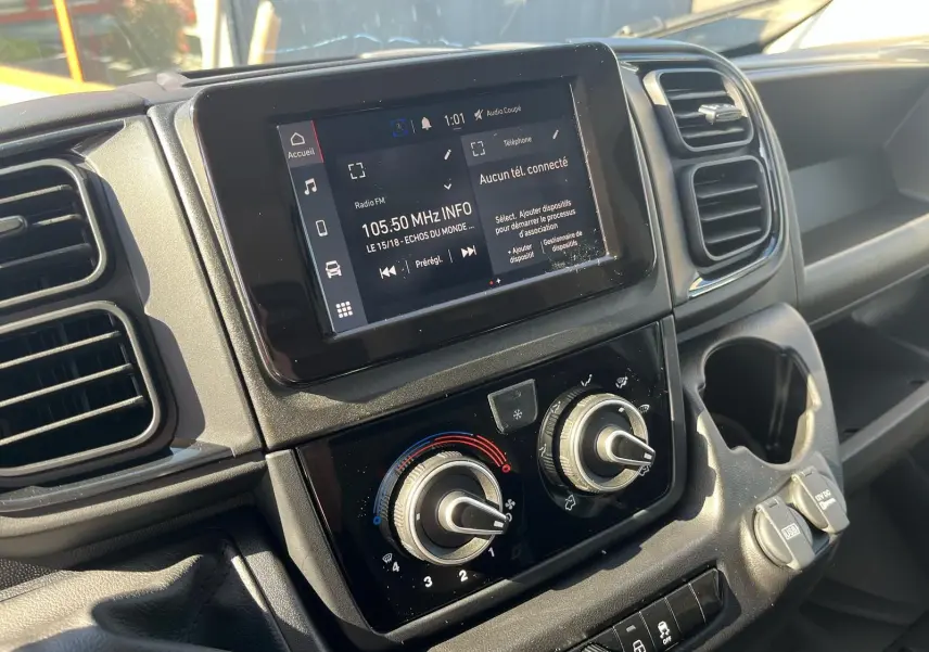 Vue rapprochée du tableau de bord du Fiat Ducato Fourgon 2023, montrant l'écran tactile et les commandes de climatisation.