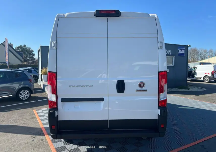 Vue arrière du fourgon blanc FIAT Ducato 2023 avec portes battantes et feux rouges verticaux.