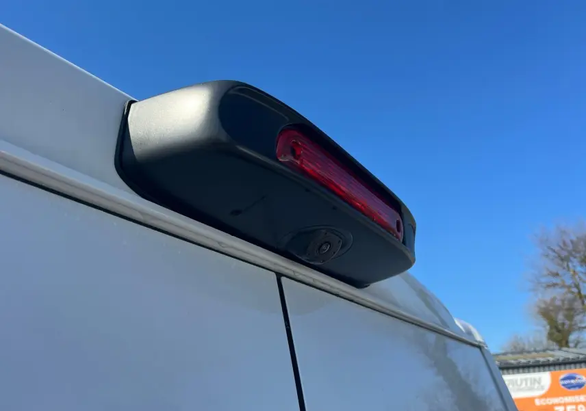 Gros plan sur la caméra de recul et le feu stop arrière du FIAT Ducato Fourgon blanc, vue en légère contre-plongée.