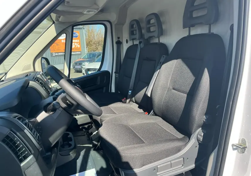 Intérieur du FIAT Ducato Fourgon blanc 2023, vue côté conducteur montrant les trois sièges noirs et le tableau de bord.