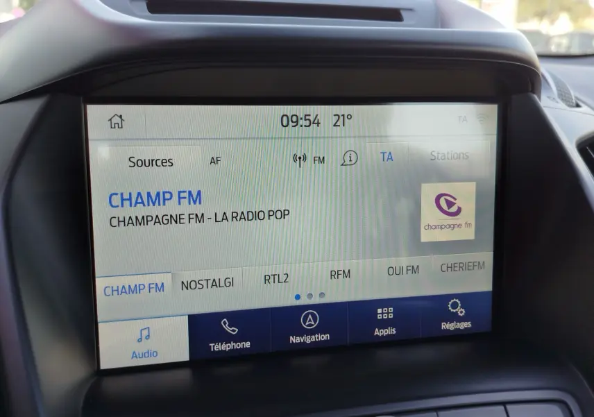 Écran tactile central du Ford Kuga 2019 affichant la radio CHAMP FM avec interface claire et boutons fonctionnels.