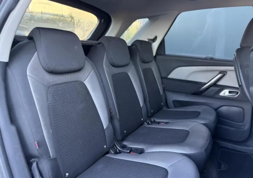 Vue latérale des sièges arrière en tissu noir et cuir gris du Citroën C4 Picasso 2017, avec stores latéraux arrière visibles.