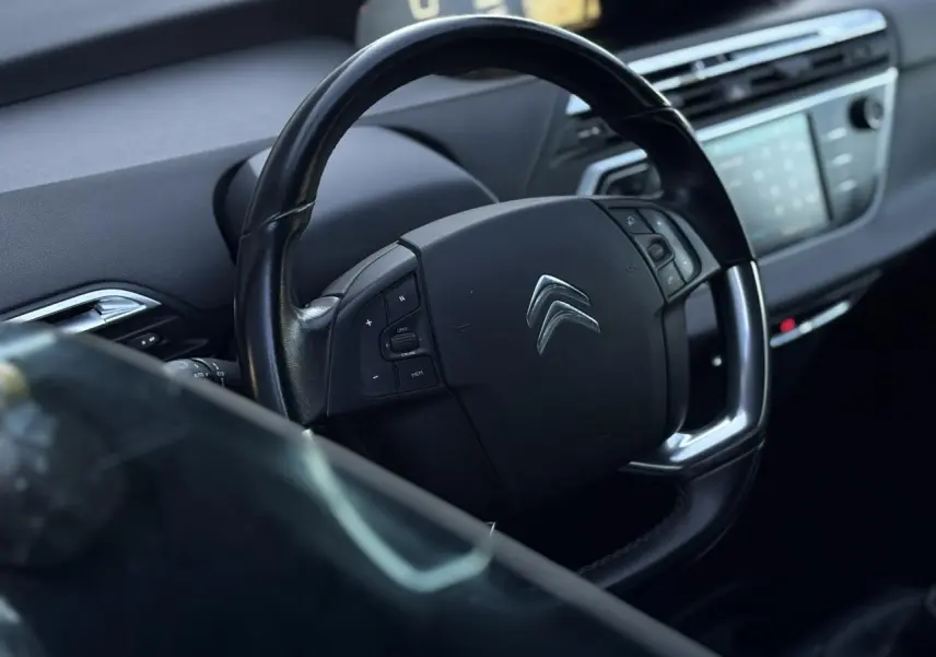 Volant en cuir noir avec commandes intégrées dans l'habitacle d'une Citroën C4 Picasso 2017, tableau de bord flou en arrière-plan.