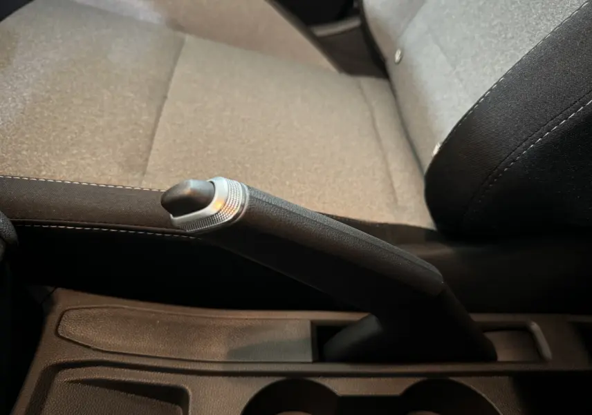 Le levier de frein à main noir en gros plan sur la console centrale, siège gris clair de Renault Clio 2025.