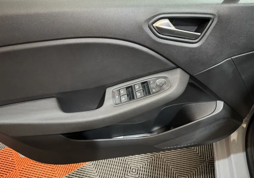 Vue rapprochée de la porte avant gauche grise de la Renault Clio 2025, avec commandes électriques des vitres et poignée argentée.