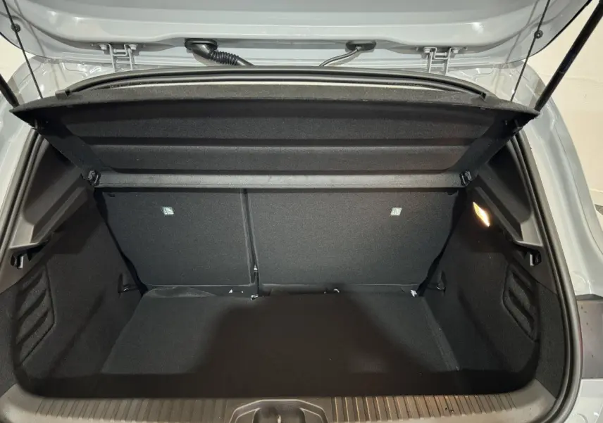 Coffre ouvert vu de l'arrière d'une Renault Clio gris clair, montrant un espace de chargement propre et bien éclairé.